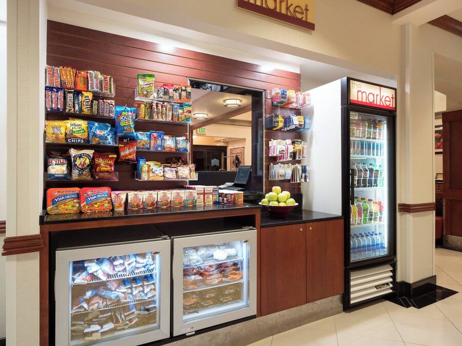 A snack and beverage kiosk with various packaged snacks, a refrigerated display, and a cash register.