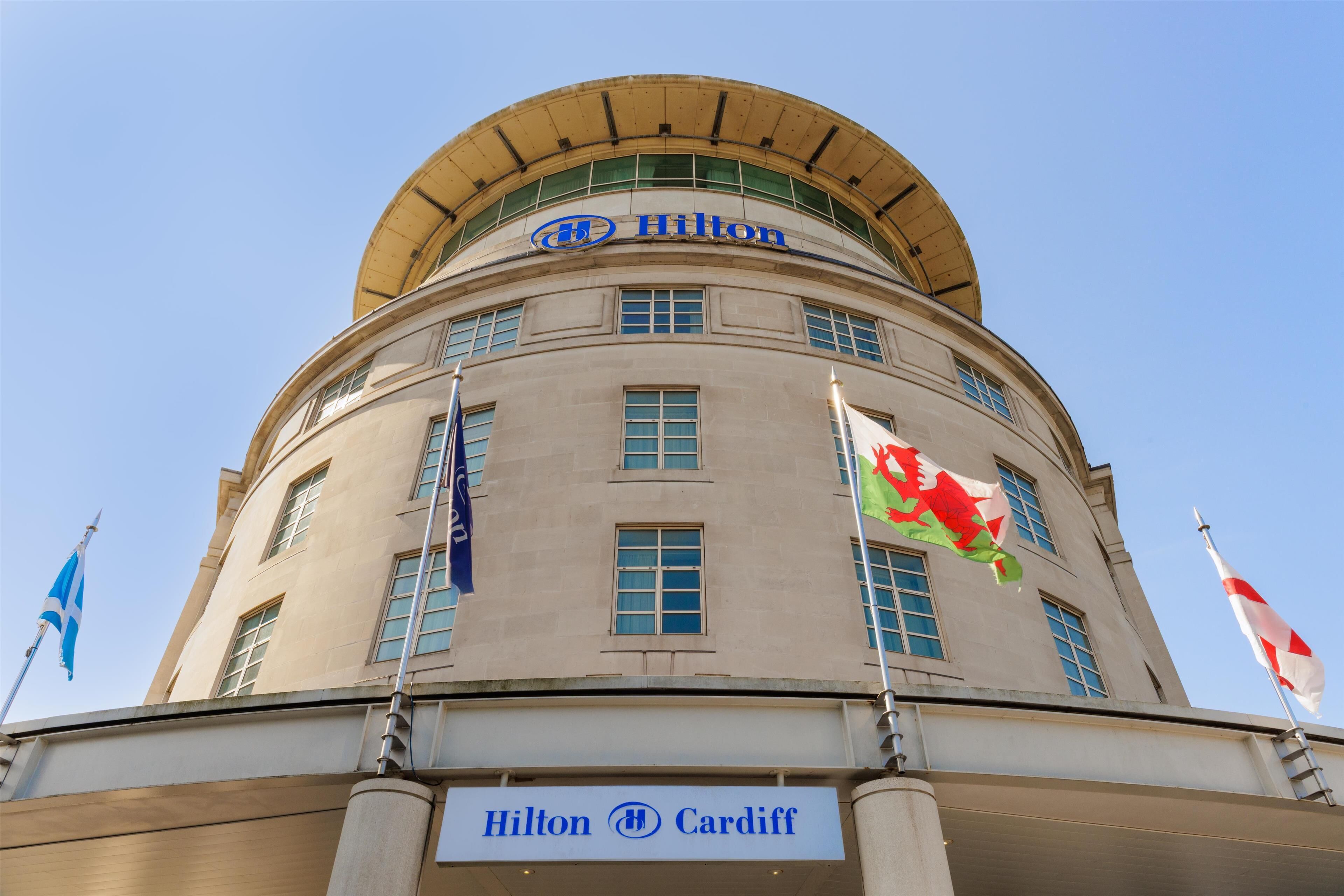 Un edificio con el logo Hilton Cardiff, que destaca por un techo circular y numerosas ventanas.