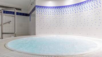 Un jacuzzi con borde de azulejos y escalera metálica.