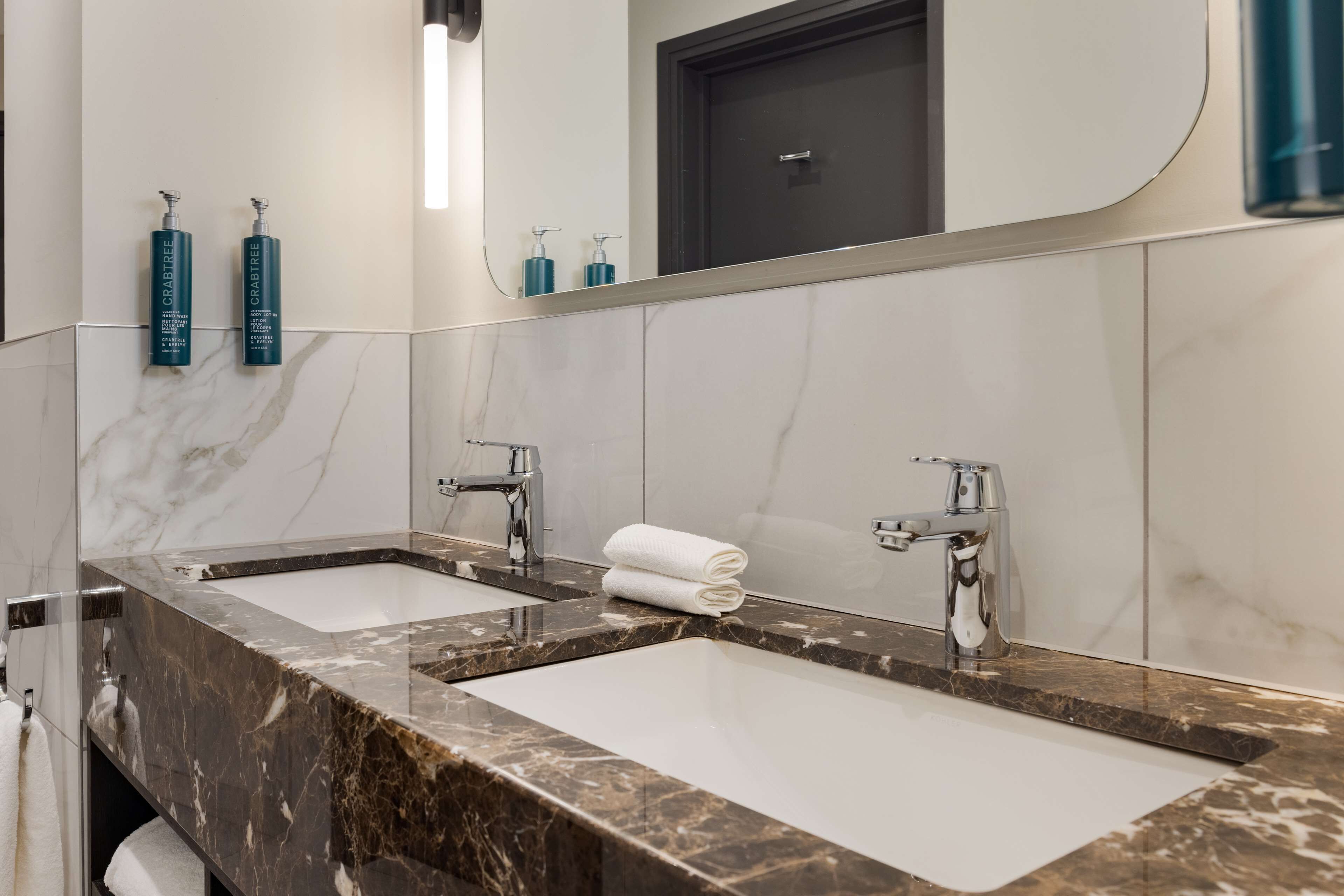 A modern bathroom with two sinks, marble countertops, and a large mirror.