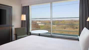 A hotel room with a large bed, a chair, a small table, and a TV.