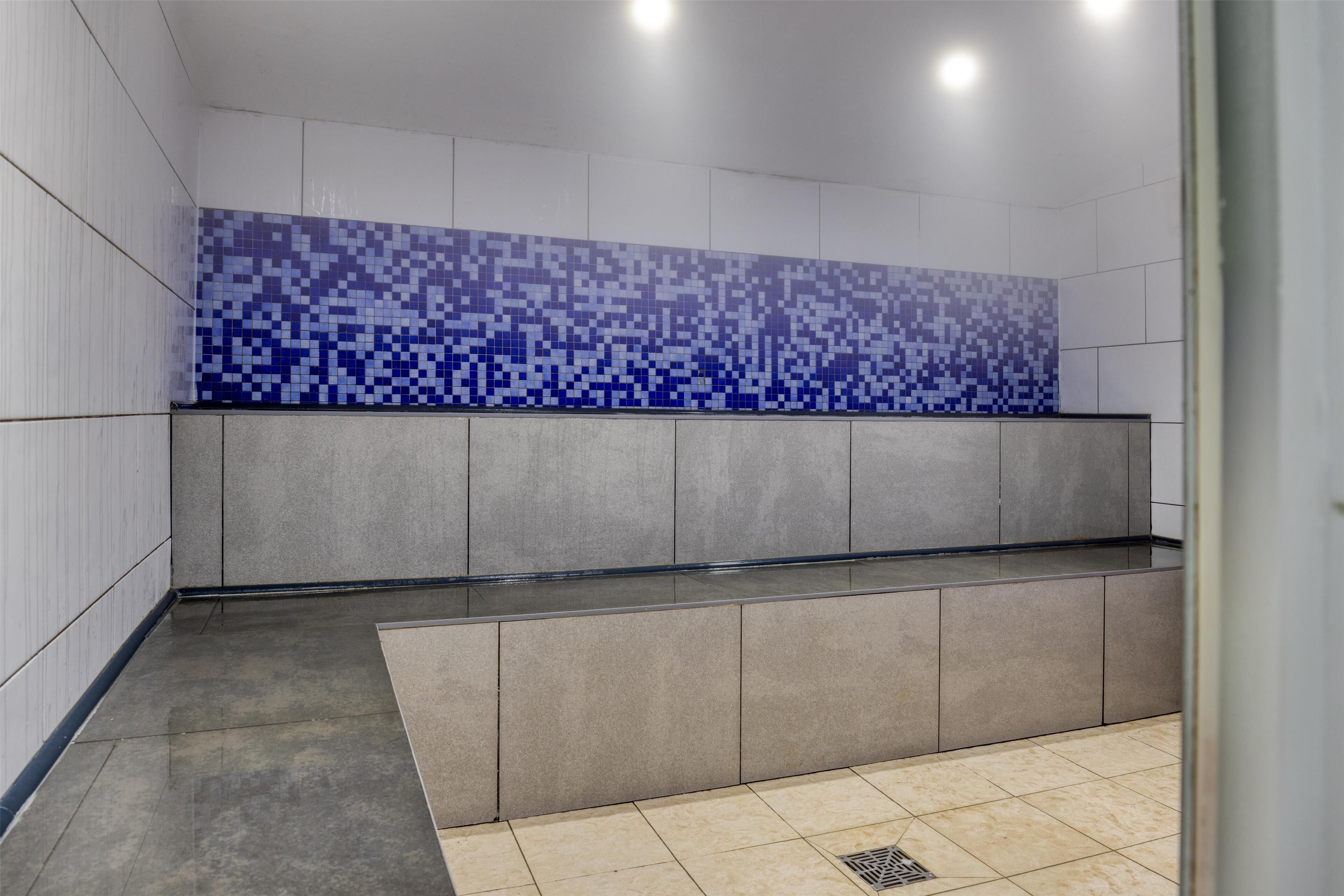 A modern bathroom with a tiled backsplash, a bench, and a shower area.