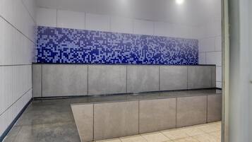 Un baño moderno con salpicadero de azulejos, un banco y zona de ducha.