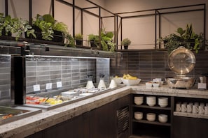 A buffet setup with various food items, a coffee station, and a mirror.