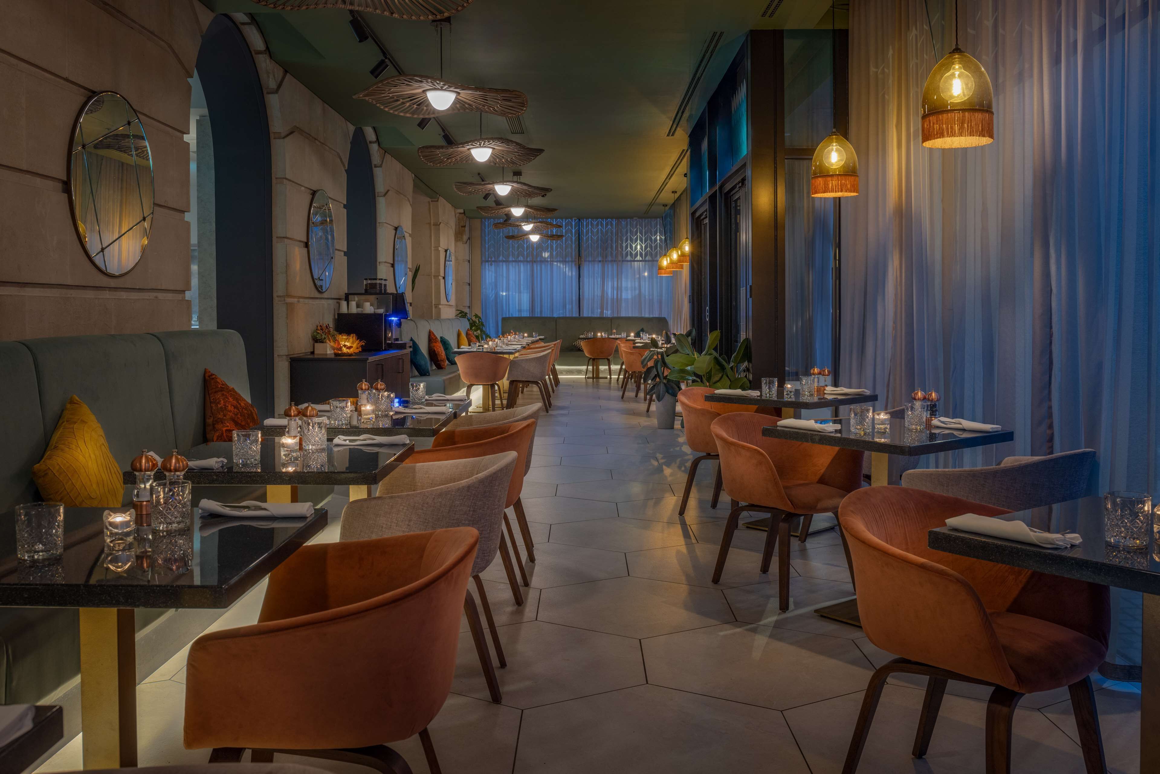 A restaurant with a long counter, multiple tables, and chairs.