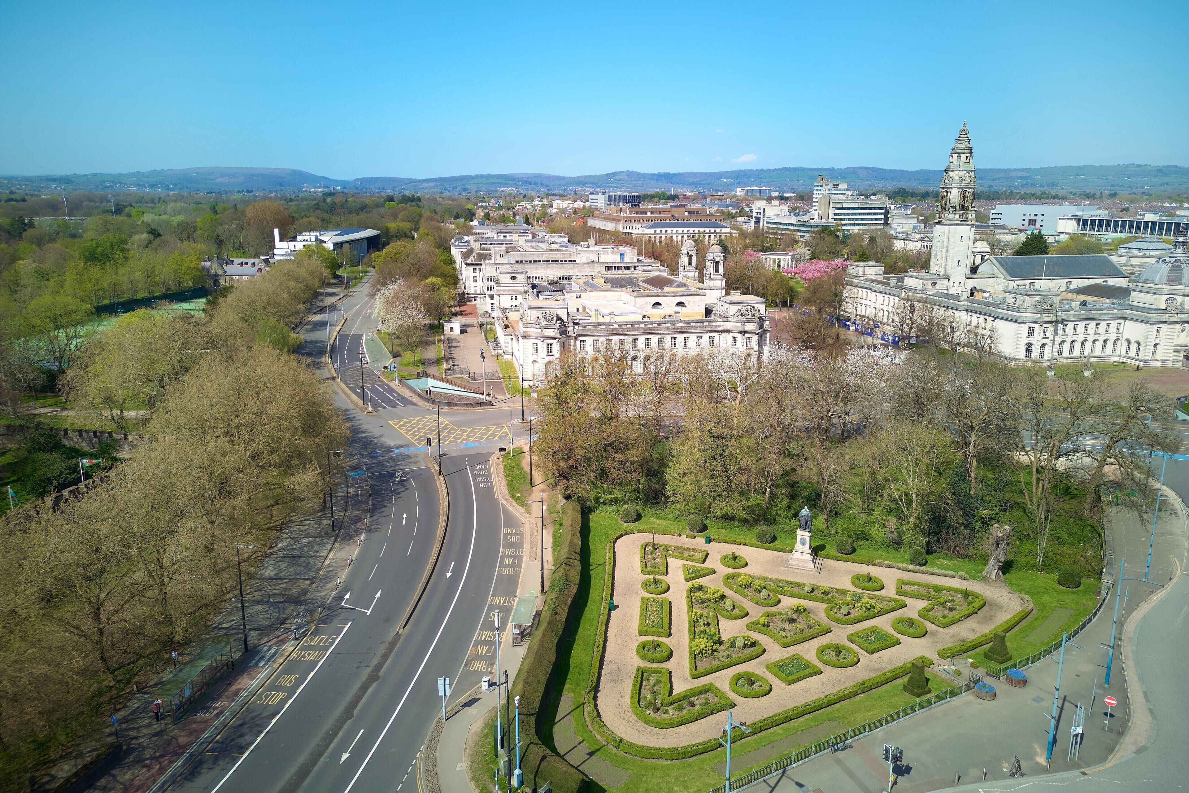 Vista aérea de un paisaje urbano que muestra un complejo de edificios destacado, una glorieta y un jardín ajardinado.