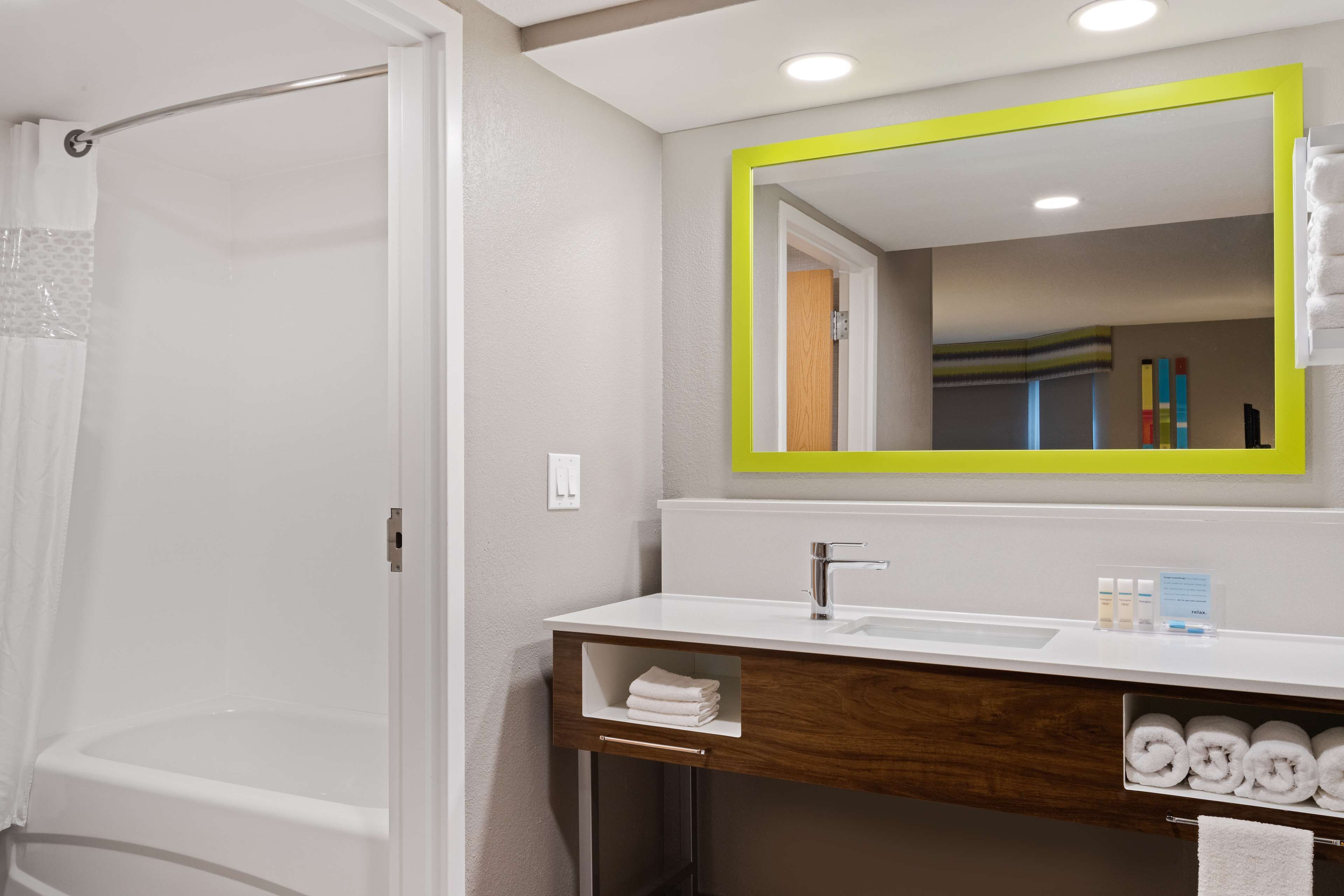 A bathroom with a shower, a sink, a mirror, and towels.