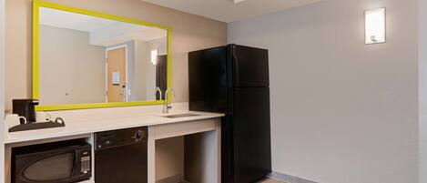 A compact kitchen with a microwave, dishwasher, and black refrigerator.