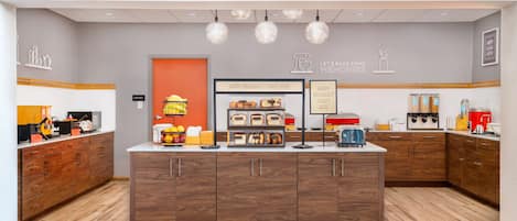 A breakfast bar with a variety of food items and a sign that reads "Happy Breakfast Starts Here".