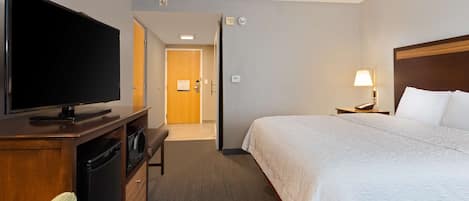 A hotel room with a bed, a television, a desk, and a lamp.