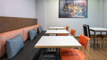 A modern dining area with a long table and benches, a patterned wall, and a cityscape artwork.