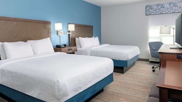 Ein Hotelzimmer mit zwei Betten, einem Schreibtisch, einem Stuhl und einem Fernseher.