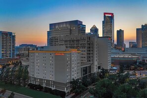 A hotel with a prominent 'Hampton Inn' sign, surrounded by modern high-rise buildings, indicating a downtown urban setting.