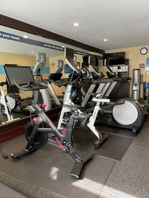 Ein Fitnessstudio mit Ergometer, Laufbändern und einer Spiegelwand.