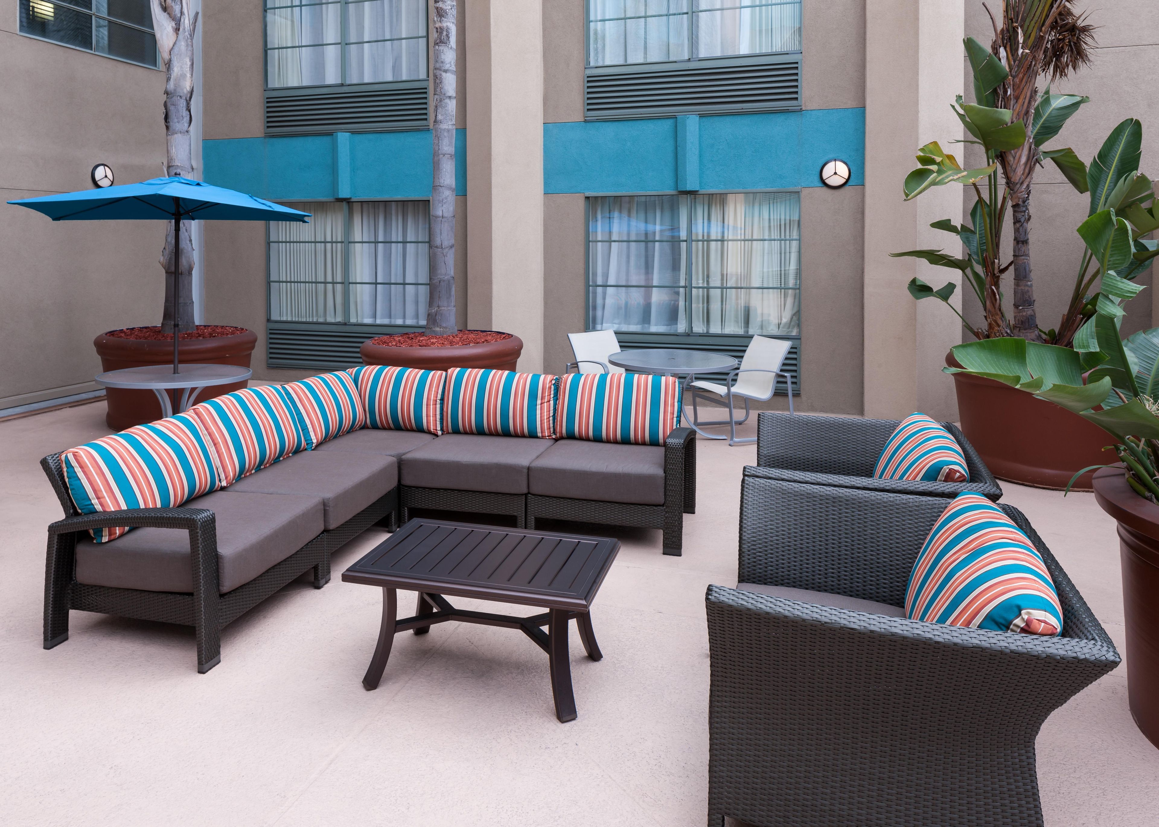 A modern outdoor seating area with a sectional sofa, a round table, and wicker chairs.