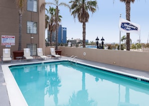 A swimming pool with lounge chairs and a Hampton Inn sign.