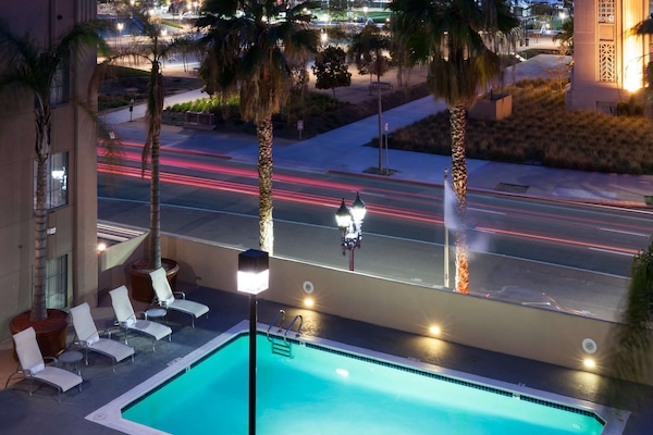 Una piscina al aire libre, sombrillas, sillones reclinables de piscina