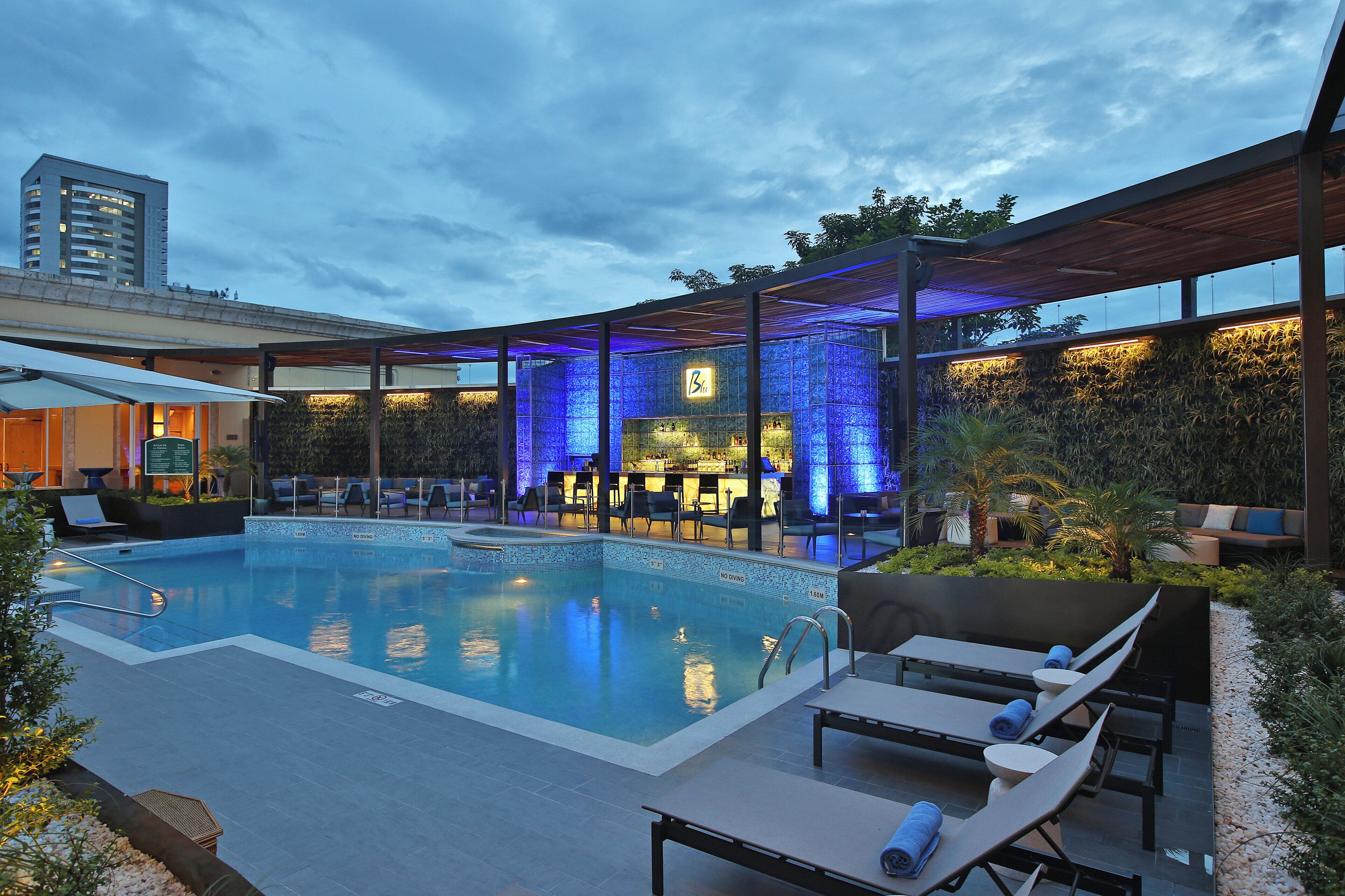 A pool area with lounge chairs, a bar, and a covered seating area.