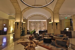 Un hall con mostrador de recepción, zona de estar y una pared decorativa.