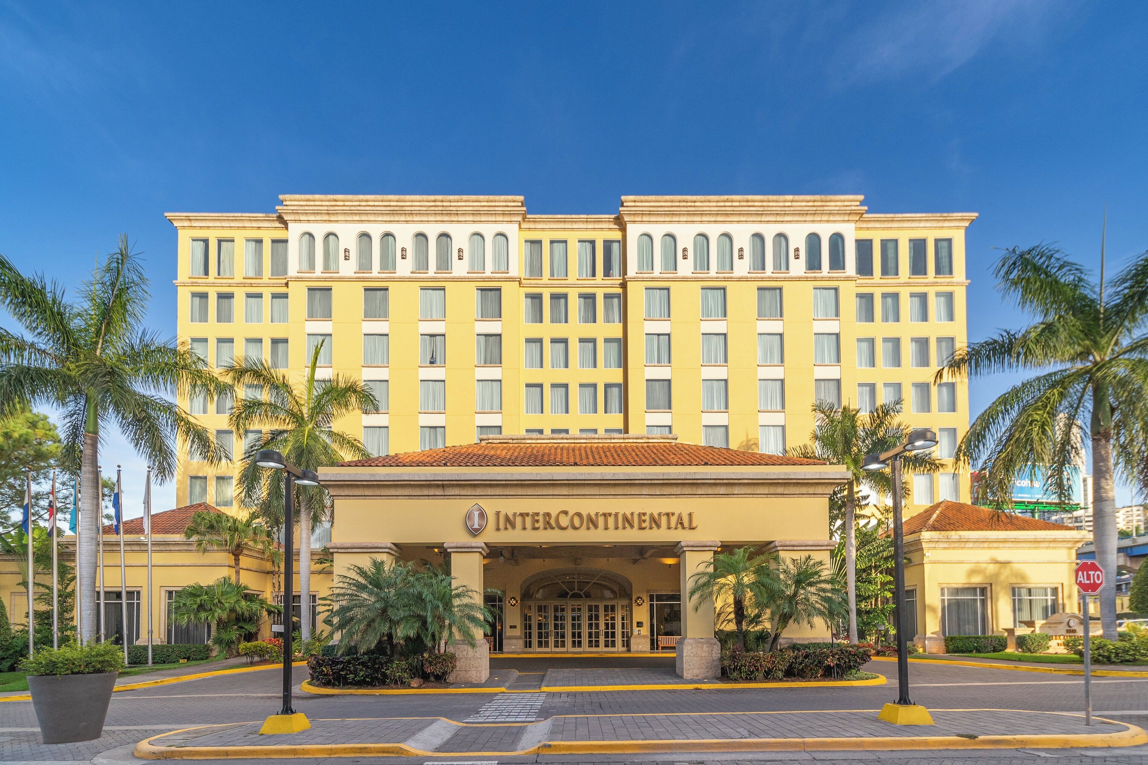 Un gran hotel Intercontinental amarillo con una fachada clásica, varios pisos y una entrada destacada.