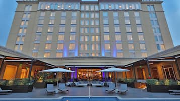 Un hotel con piscina, mesas al aire libre y una entrada bien iluminada.