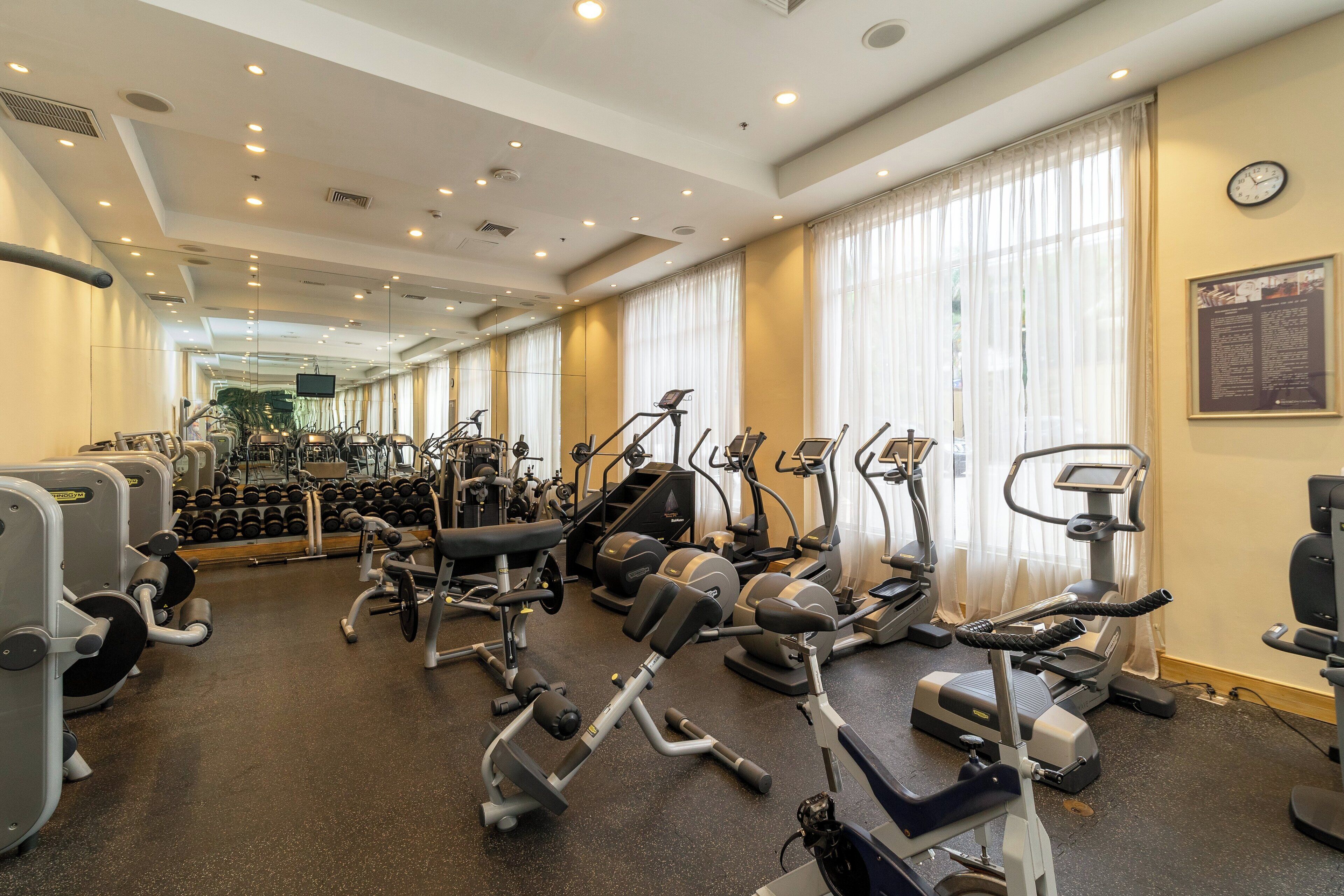 A gym with various exercise equipment, including treadmills, ellipticals, and weight machines.
