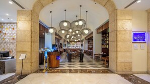 Un vestíbulo de hotel con mostrador de recepción, una zona de estar y un letrero de tienda.