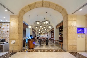 Eine Hotelhalle mit einer Rezeption, einer Sitzecke und einem Hinweisschild auf einen Markt.