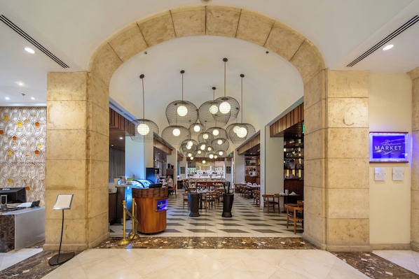 Un vestíbulo de hotel con mostrador de recepción, una zona de estar y un letrero de tienda.