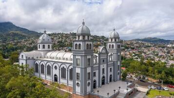 Una iglesia grande con dos cúpulas destacadas y un campanario, rodeada por un pueblo en colinas.