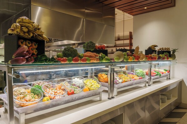 A buffet with a variety of fruits, vegetables, and prepared dishes.