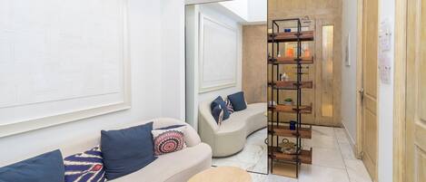 Een moderne lobby met een gebogen bank, een klein rond tafeltje en een wandplank met diverse spullen.
