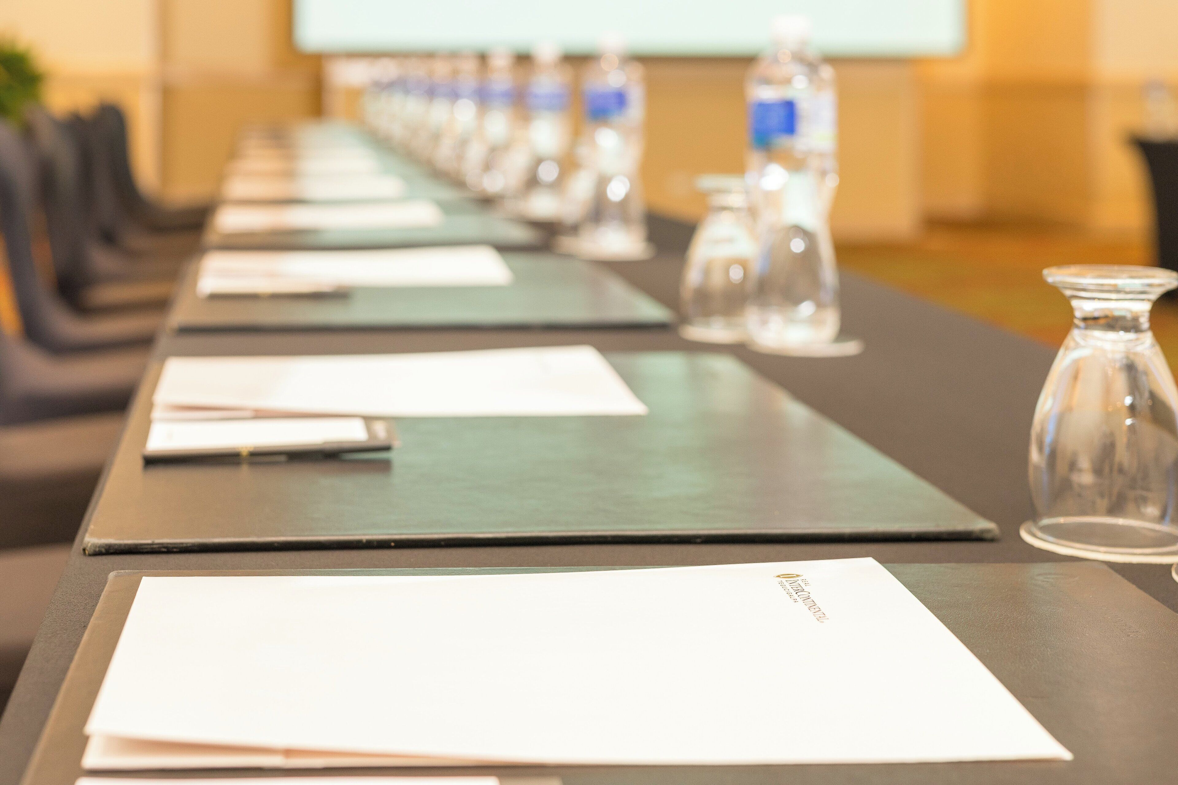 Une table de conférence avec des bouteilles d’eau, des documents et un ordinateur portable.