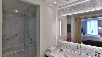 Un baño moderno con ducha de vidrio, un espejo grande y un lavamanos blanco.