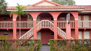 A two-story building with a red facade, a central staircase, and balconies. - Gables Inn  (Coral Gables)