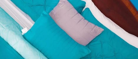 Un lit avec une literie aux couleurs turquoise et blanche et une tête de lit en bois.