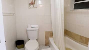A small bathroom with a toilet, a shower, and a picture of a llama on the wall.