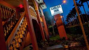 A Gables Inn sign with a staircase and palm trees in the background. - Gables Inn  (Coral Gables)