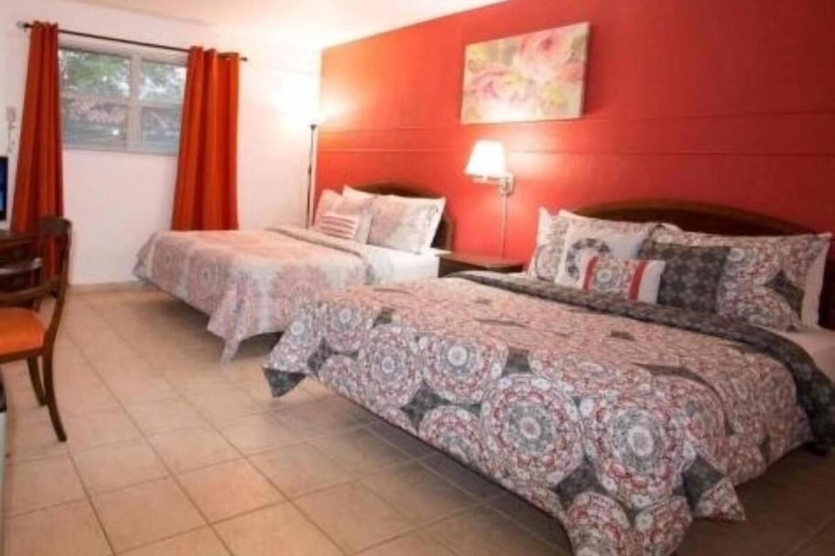 A room with two beds, a desk, and a window with curtains.
