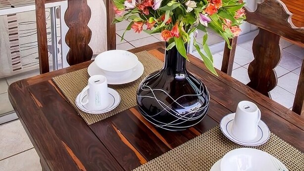 Ein Essbereich mit Tisch für zwei Personen, einem Blumenstrauß und einem Fernseher im Hintergrund.