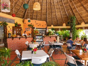 Un espace de restauration intérieur avec des murs en briques, un toit de chaume et des tables accompagnées de chaises.