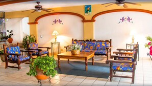 A spacious living room with wooden furniture, a ceiling fan, and decorative wall art. - Hotel Vallartasol (Puerto Vallarta)