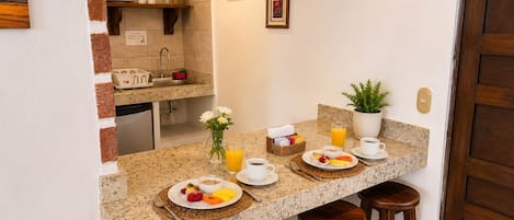 A kitchen with a breakfast setup including plates of food, a coffee cup, and a juice glass.