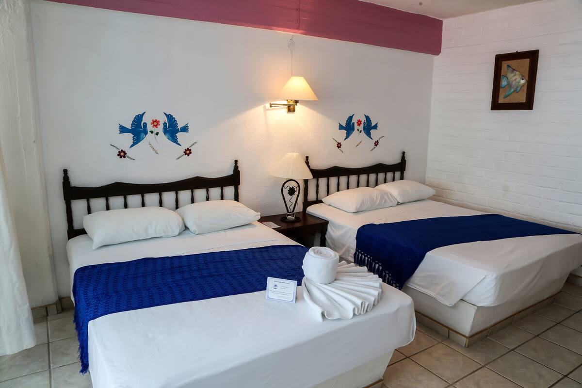 Een hotelkamer met twee bedden, een nachtkastje, een lamp en wanddecoratie.