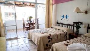 Une chambre d’hôtel avec deux lits, un balcon, un coin repas et un mur agrémenté d’éléments décoratifs.