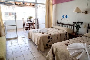 Une chambre d’hôtel avec deux lits, un balcon, un coin repas et un mur agrémenté d’éléments décoratifs.