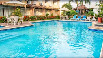 Relax by the pool surrounded by lush greenery and comfortable lounge chairs.