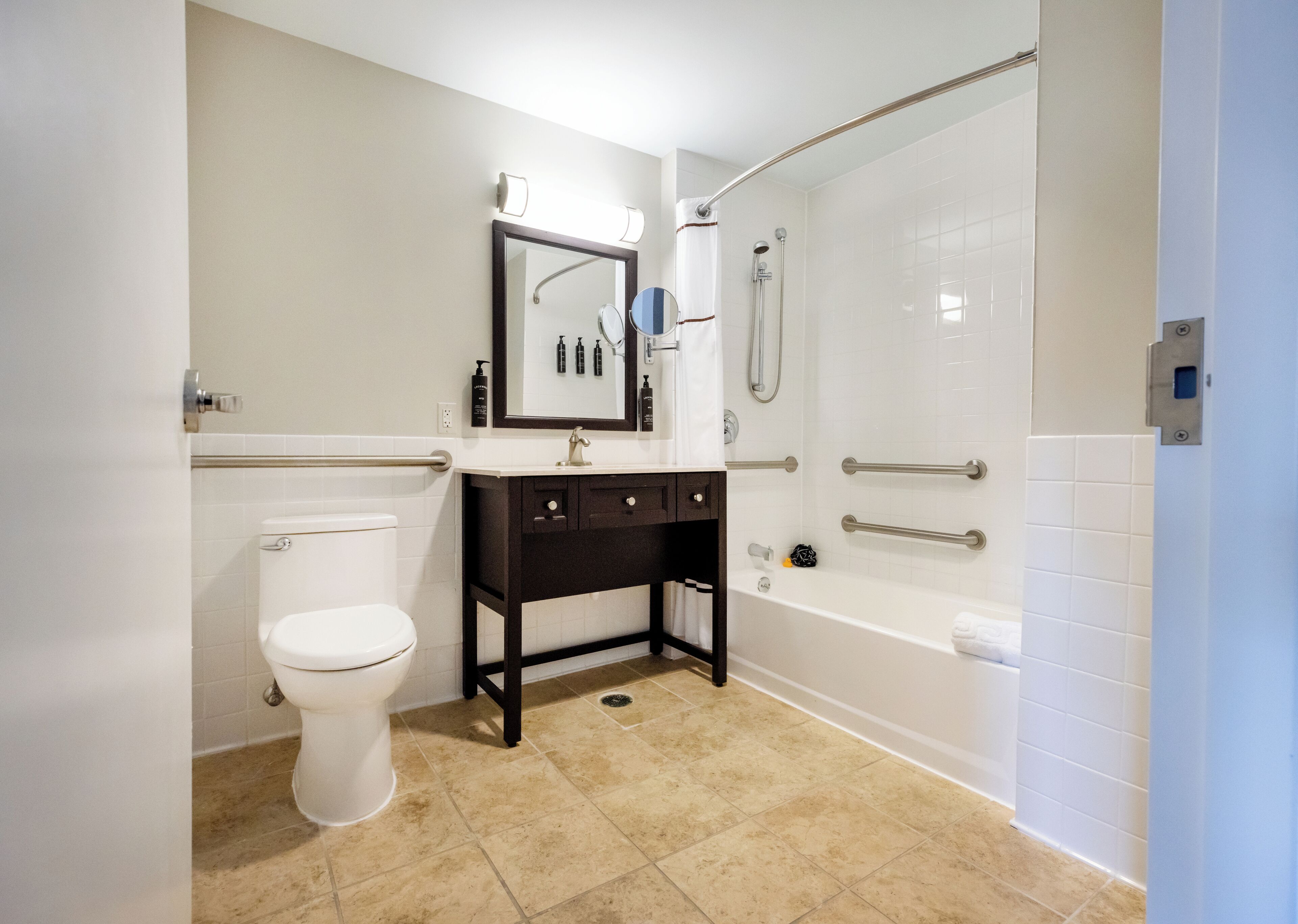A bathroom with a toilet, sink, mirror, and shower.