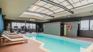 An indoor swimming pool with lounge chairs, exercise equipment, and a lifebuoy on the wall. - Mantra on Hay Perth (East Perth)