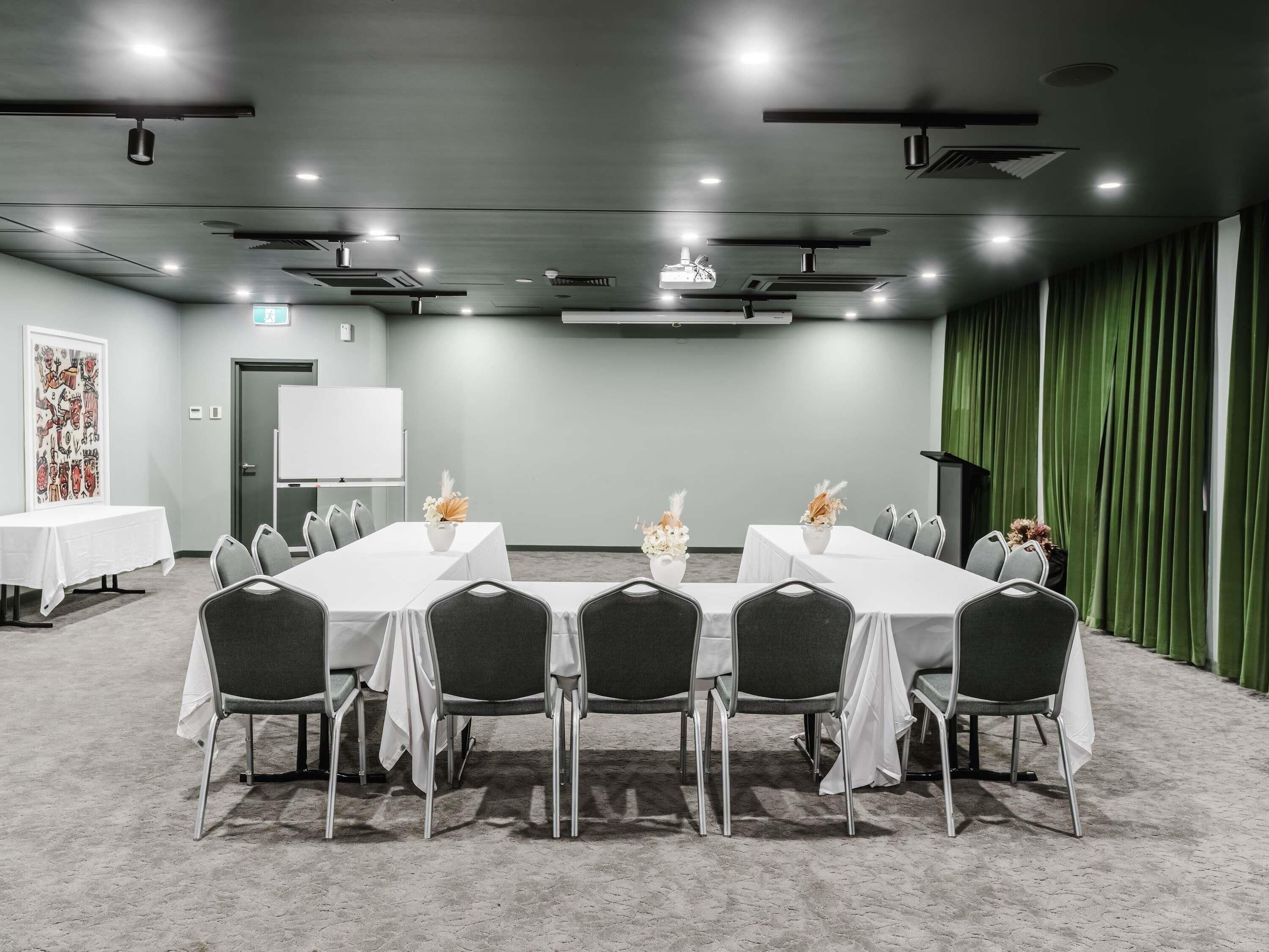 A conference room with a whiteboard, a projector, and a table with chairs.
